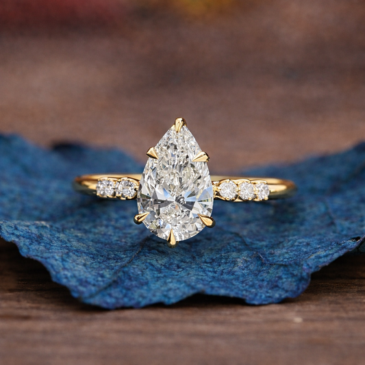Gold ring with a pear-shaped diamond on a blue leaf