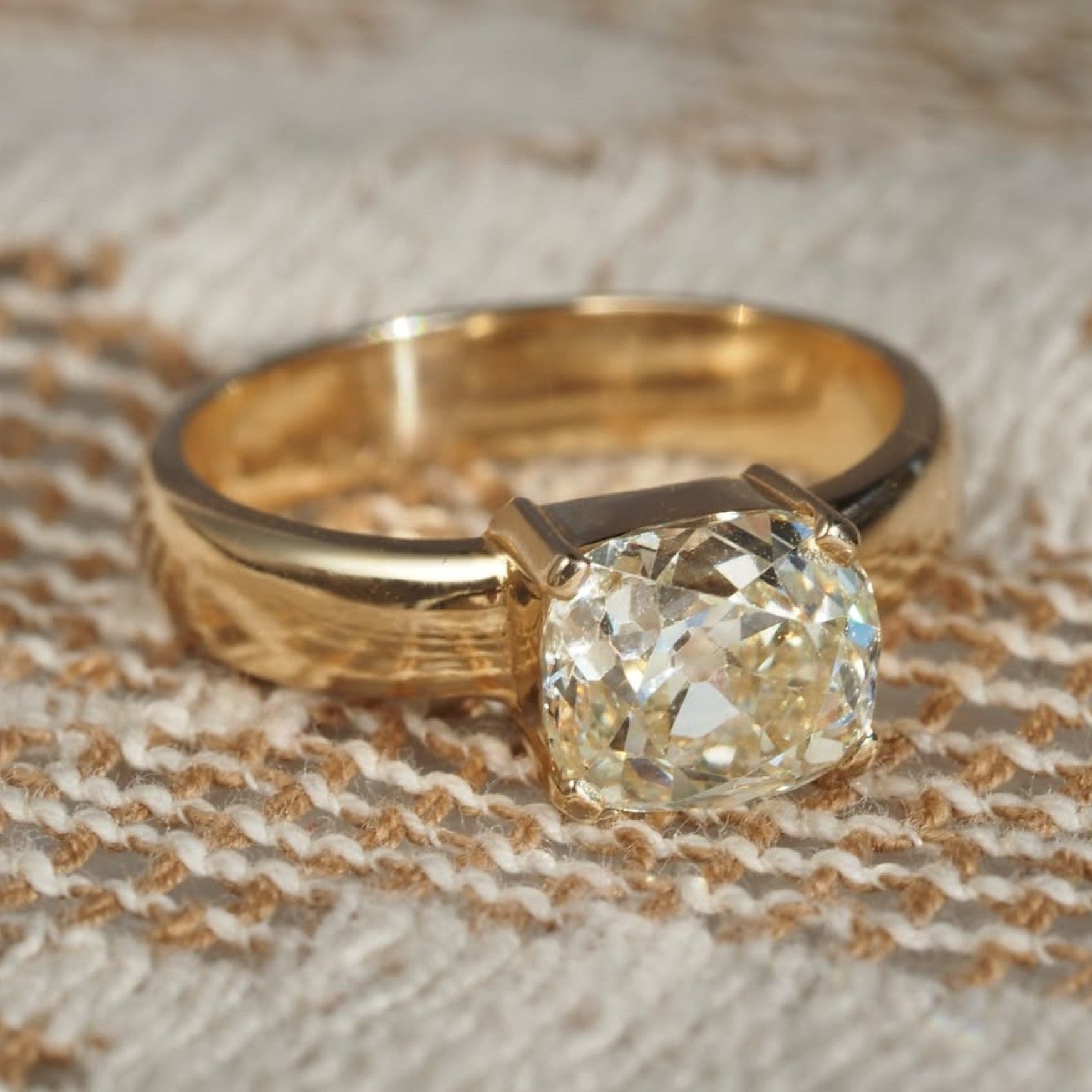 Gold ring with a large diamond on a textured fabric 