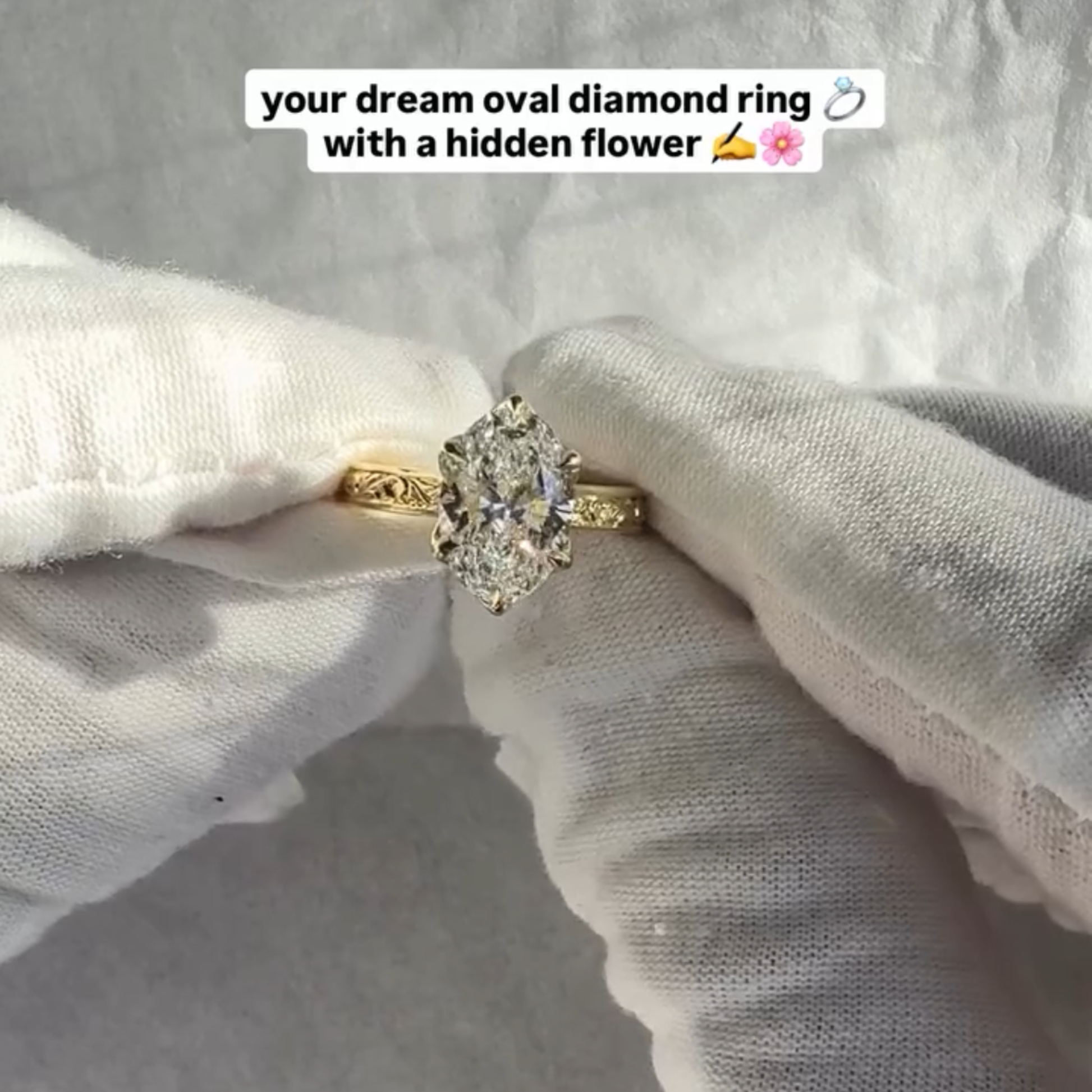 Gold oval diamond ring held between two hands wearing white gloves 