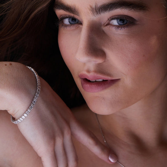Close-up of a woman's face with a focus on her hand wearing a bracelet.