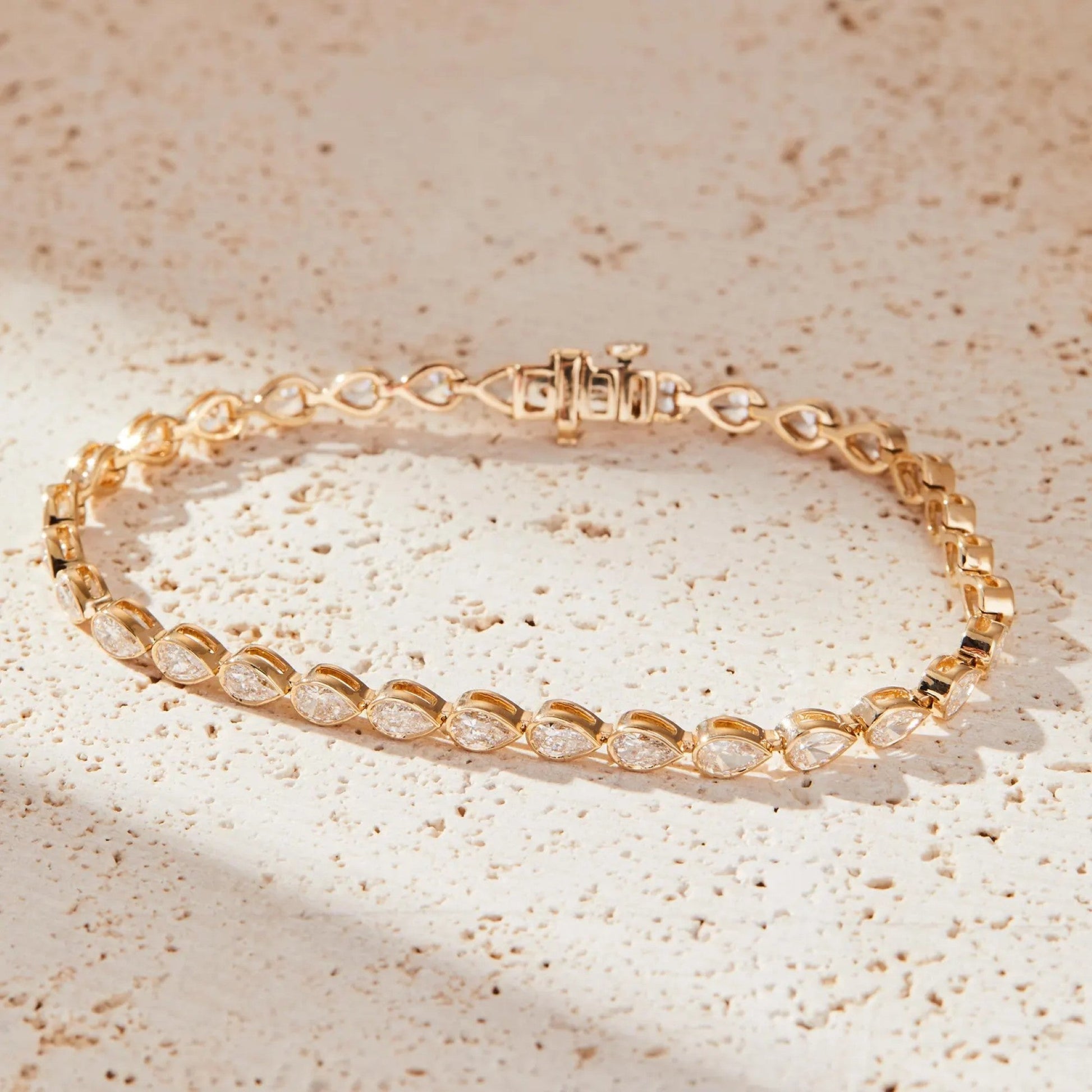 Gold bracelet with clear stones on a beige textured 