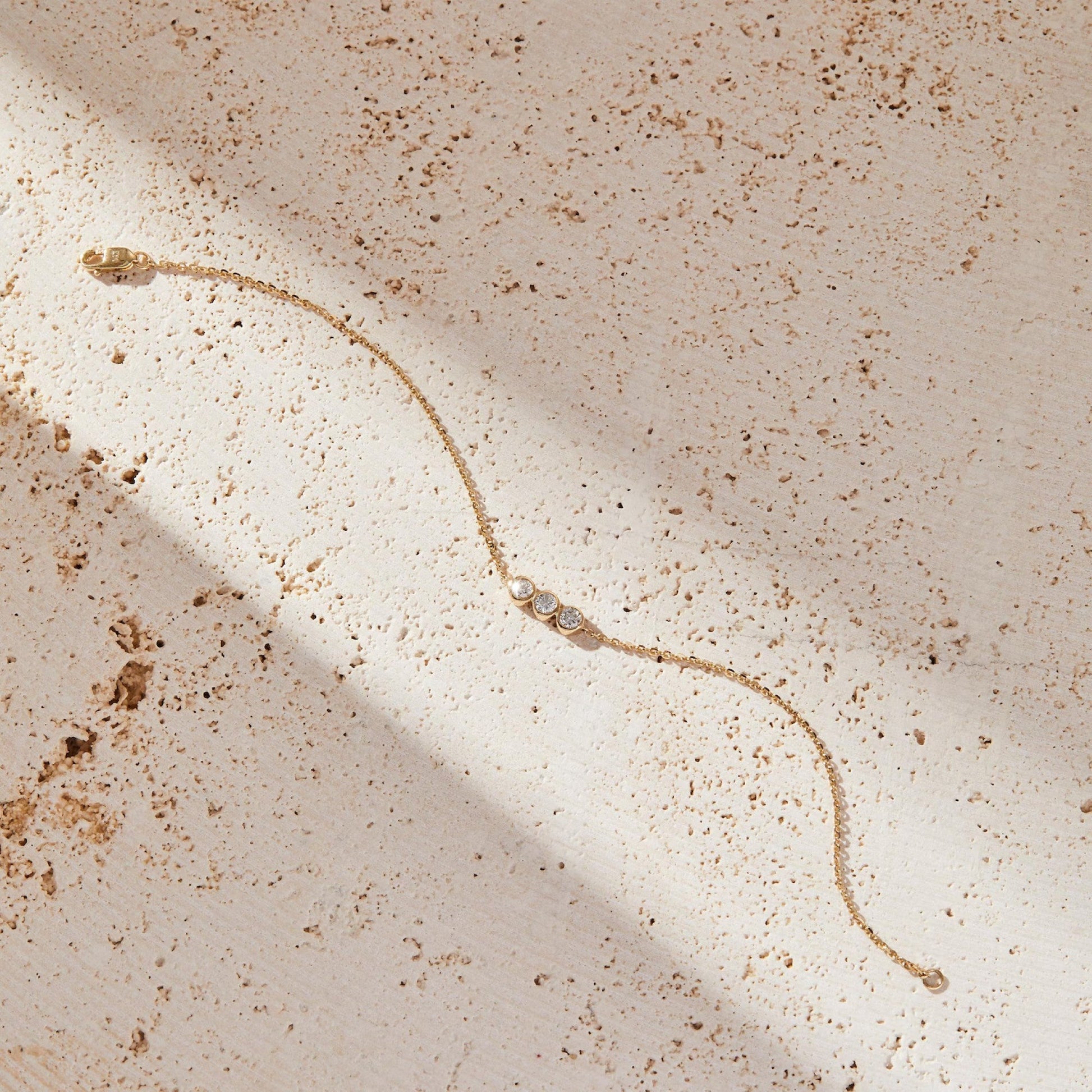 Gold bracelet on a textured beige surface