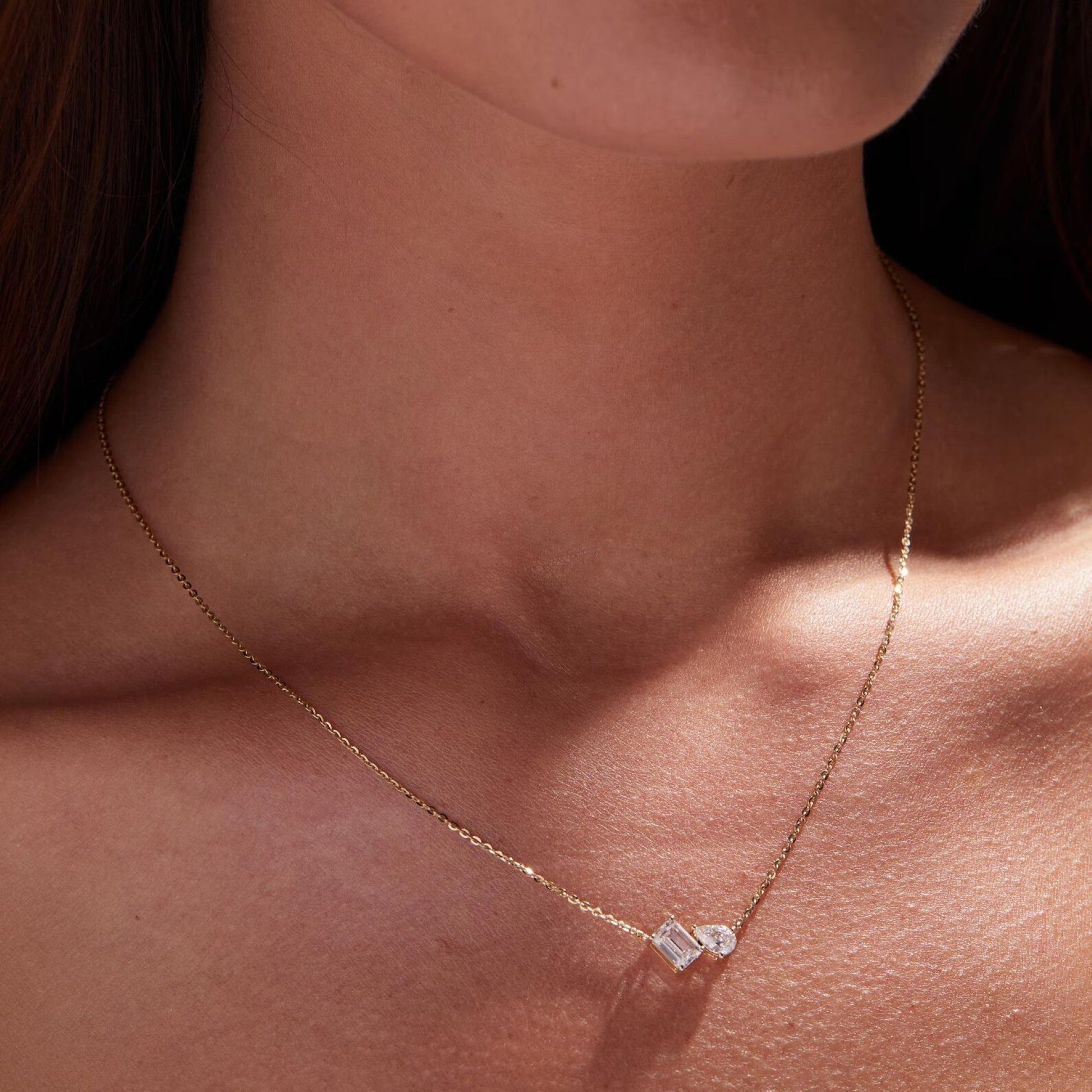 Gold necklace with a diamond pendant on a person's neck