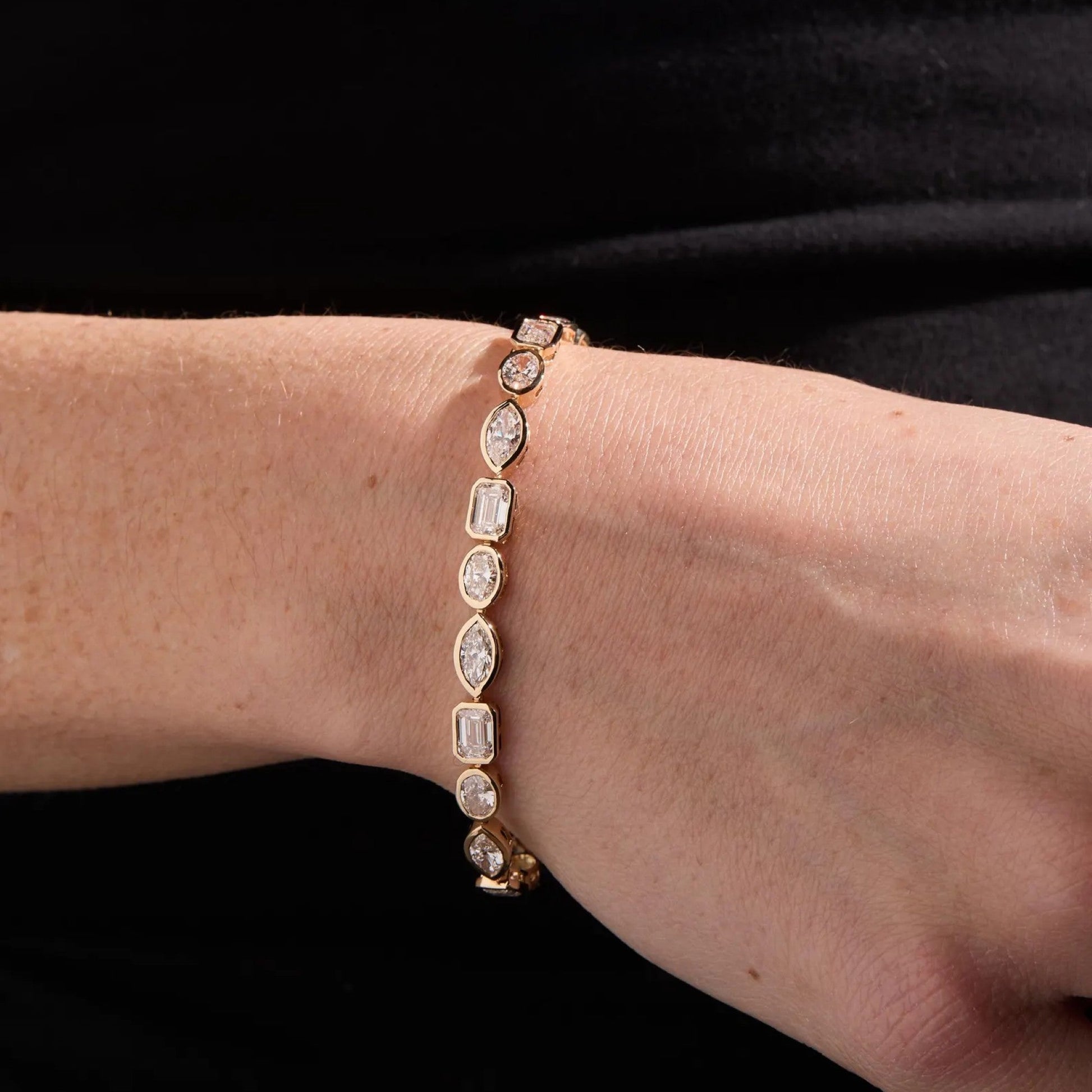 Bracelet with clear gemstones on a wrist against a black background