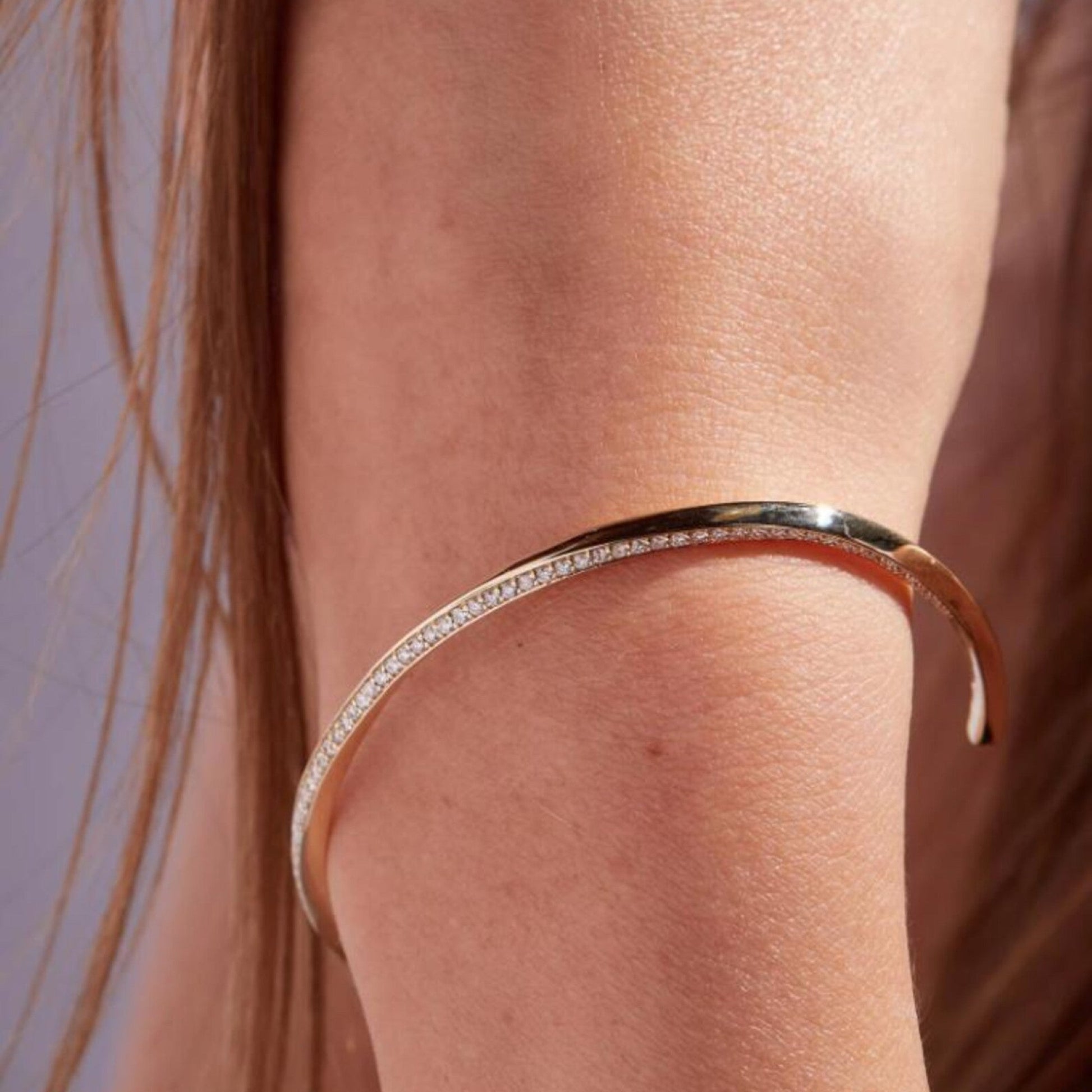 Close-up of a person's arm wearing a silver bracelet with small stones.