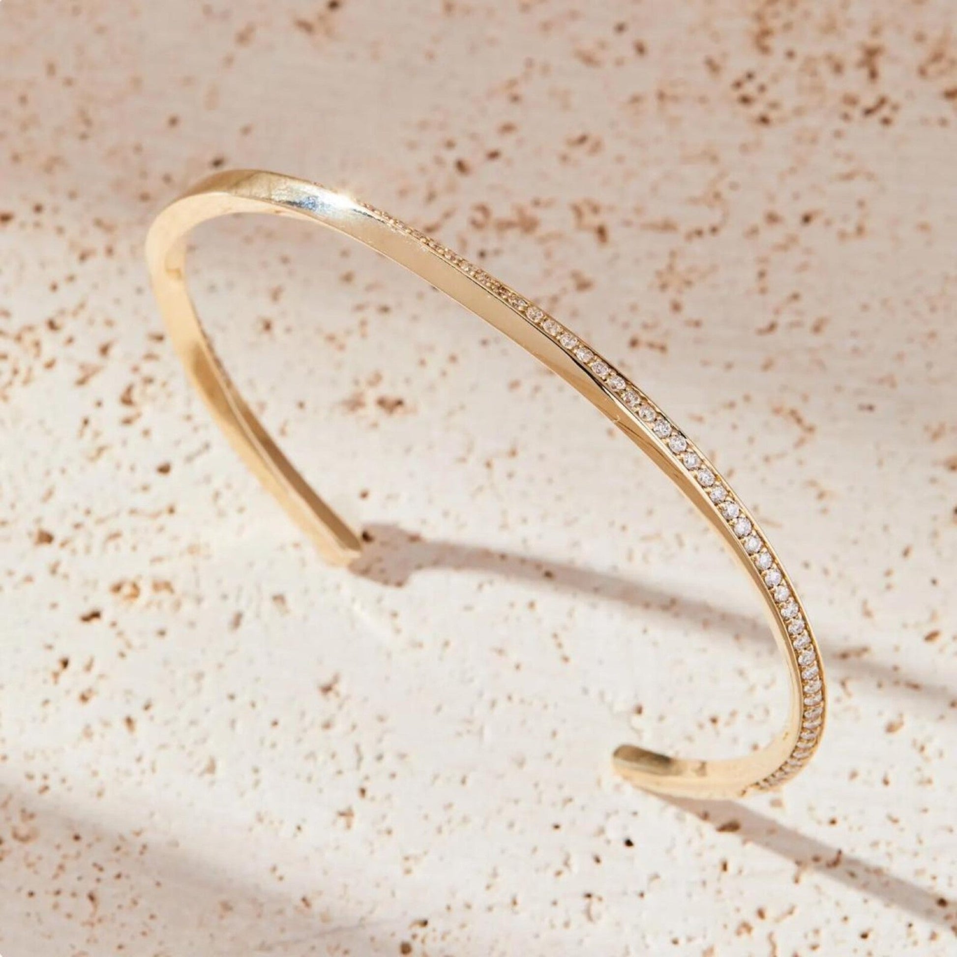 Gold bracelet with small diamonds on a beige textured 