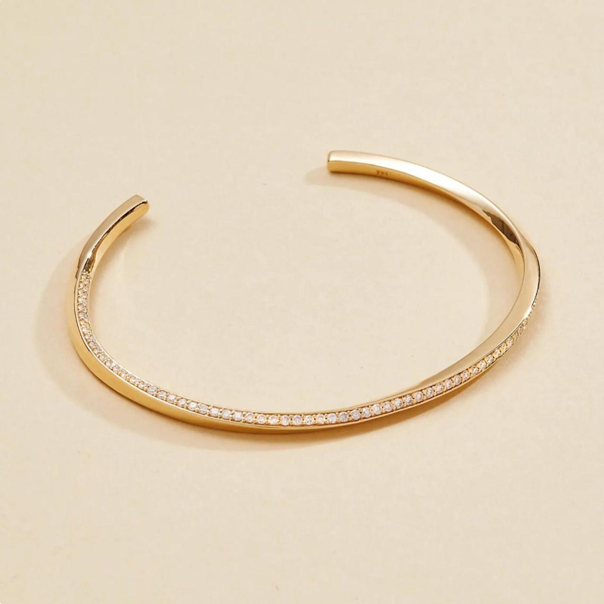 Gold bracelet with small stones on a beige 